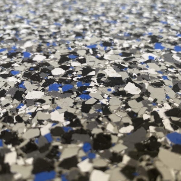 The image shows a close-up of a speckled surface with black, white, and blue fragments, possibly a floor with a terrazzo or epoxy finish.